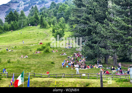 Col du Lys, Piémont, Italie. Juillet 2019. Les gens à la buvette de profiter de la pente de la montagne avec une grande pelouse verte à picni Banque D'Images