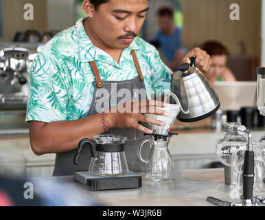 Vie candide shot of indonesian ethniques barista et propriétaire de petite entreprise la préparation du café bio-équitable dans un café branché Banque D'Images