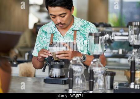 Vie candide shot of indonesian ethniques barista et propriétaire de petite entreprise la préparation du café bio-équitable dans un café branché Banque D'Images