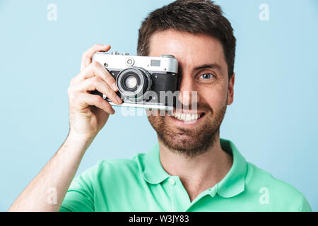 Portrait d'un bel homme barbu portant des vêtements isolés sur fond bleu, de prendre une photo avec l'appareil photo Banque D'Images