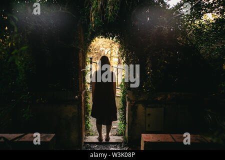 Femme debout encadré dans une porte voûtée couverte de légumes verts à feuilles dans le jardin de la Concepcion Historical-Botanical, Malaga, Espagne Banque D'Images