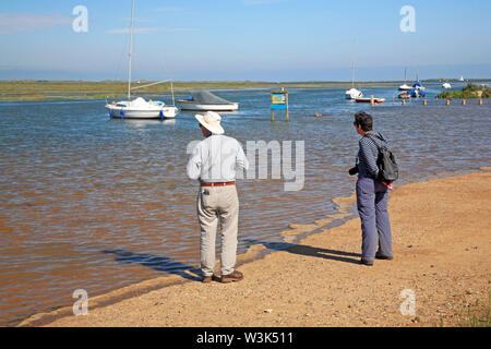Un vieux couple à la sur le port canal sur la côte nord du comté de Norfolk à Blakeney, Norfolk, Angleterre, Royaume-Uni, Europe. Banque D'Images