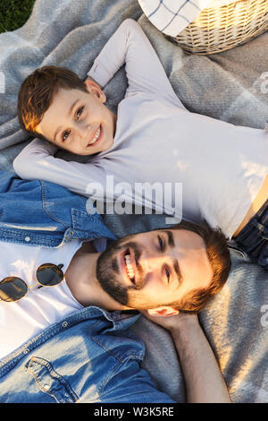 Image d'un jeune homme heureux d'avoir du plaisir avec son petit frère ou fils outoors en parc se trouve. Banque D'Images