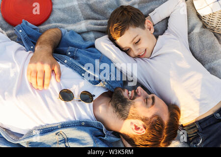 Image d'un jeune homme heureux d'avoir du plaisir avec son petit frère ou fils outoors en parc se trouve. Banque D'Images