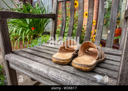 Une paire de sandales en cuir pour hommes sur un siège en bois dans un jardin. Banque D'Images