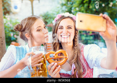 Best Friends in Bavarian Tracht faisant un avec le téléphone Selfies Banque D'Images