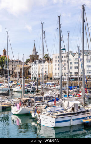 Dans le port des yachts amarrés en face de la ville, église St Peter Port, Guernsey, Channel Islands UK Banque D'Images