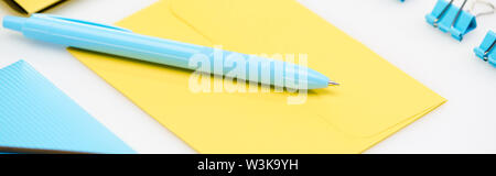 Bleu de dossier, trombones et un stylo sur l'enveloppe jaune sur fond blanc Banque D'Images