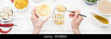 Portrait de femme l'ajout de couscous bocal en verre sur la table en bois blanc, vue panoramique tourné Banque D'Images