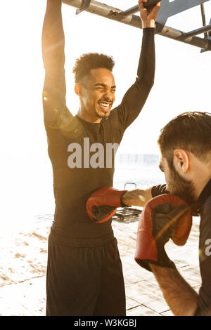 Deux jeunes motivés sportifs sains en plein air sur la plage, ensemble d'entraînement, des exercices de boxe Banque D'Images