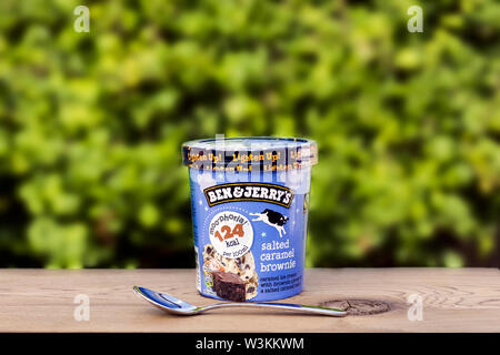 Ben & Jerry's brownie caramel salé la crème glacée sur la table en bois naturel à l'extérieur contre l'arrière-plan vert blured. Banque D'Images