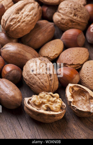 Libre de différents types de fruits secs dont les pacanes, les amandes et les noisettes en coque sur table en bois rustique Banque D'Images