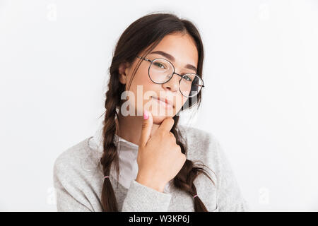 Gros plan Photo of teenage girl wearing eyeglasses toucher son menton et looking at camera isolated over white background Banque D'Images