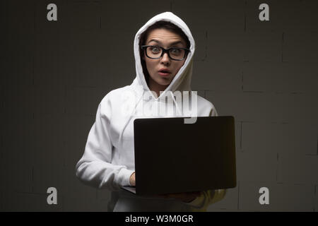 Une femme dans un capot est à l'aide d'un ordinateur portable. Hacker est à l'aide d'un ordinateur portable. Banque D'Images
