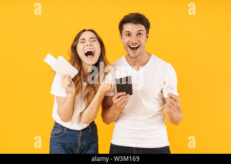 Portrait de couple heureux joie en maintenant l'ensemble de musique avec passeport et carte de crédit plus isolé sur fond jaune Banque D'Images