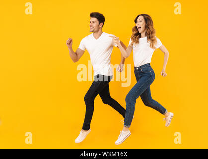 Portrait of caucasian couple man and woman smiling at camera while running ensemble plus isolé sur fond jaune Banque D'Images