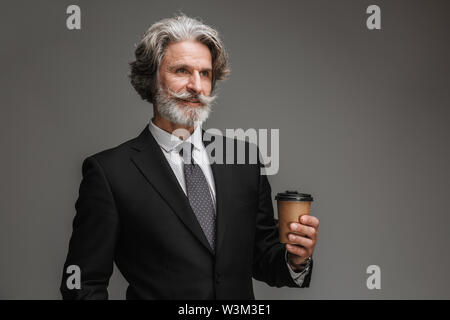 Image d'adultes non rasé businessman wearing costume noir officiel lawn coupe papier sur fond gris isolé Banque D'Images