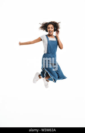 Image of african american woman réjouissance et de sauter tout en écoutant de la musique avec un casque isolé sur fond blanc Banque D'Images