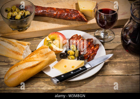 Le déjeuner du laboureur en Espagne : Chorizo, fromage de chèvre, olives, pomme, du pain et un verre de vin Banque D'Images