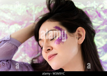 Woman with purple glitter on cheek Banque D'Images