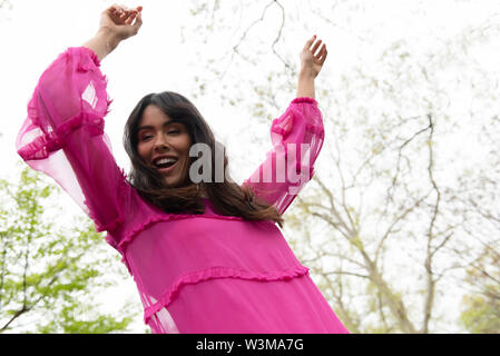 Smiling woman dancing en robe rose Banque D'Images