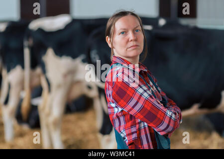 La productrice en enclos sur une ferme d'élevage laitier, portrait de satisfait fier avec son cowgirl du bétail en étable ranch Banque D'Images