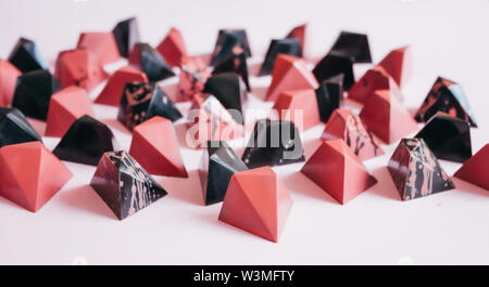 Pralines au chocolat noir sur fond rose, coloré en noir et corail. Banque D'Images