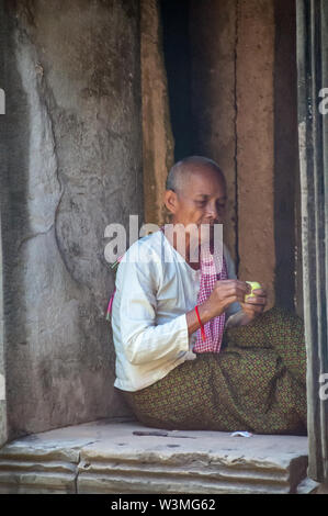 Un bouddhiste est assis dans la fraîcheur à l'intérieur d'un ancien temple d'Angkor Wat Banque D'Images