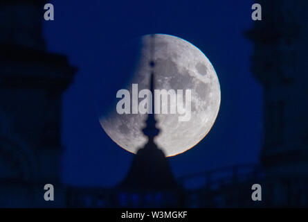 Schwerin, Allemagne. 16 juillet, 2019. La pleine lune, qui a déjà partiellement entré l'ombre de la terre en ce moment, s'allume sur le château de Schwerin. Les badauds peuvent observer une éclipse lunaire partielle sur l'Allemagne. Entre 22h le mardi et 13h le mercredi des parties de la terre se trouvent dans le noyau de la ombre de la terre et la lune brillent dans le ciel rouge rouille. Credit : Jens Buettner/dpa-Zentralbild/dpa/Alamy Live News Banque D'Images