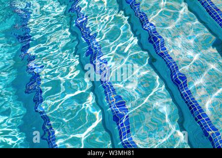 Motifs abstraits formés par la forte lumière du soleil sur la surface de l'eau dans une piscine semblable à David Hockney's tableaux célèbres Banque D'Images