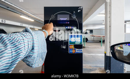 Bâle, Suisse - Jun 5, 2018 : POV man main insérer dans la barrière côté ticket ticket machine pour quitter le stationnement Français Banque D'Images