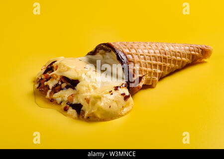 Vue côté saveur mangue ice cream cone avec fondu d'arachide sur fond jaune Banque D'Images