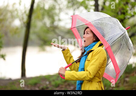 Femme marche dans la pluie en forêt d'automne. Jolie fille se sent les gouttes de balade en forêt par le lac à l'automne. Mixed Race Woman modèle féminin asiatique avec drôle ecxpression. Banque D'Images