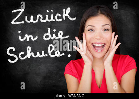 Zuruck in die Schule - screaming étudiant allemand heureux retour à l'école écrit en allemand sur tableau noir par l'enseignante. Smiling woman langue enseigner l'allemand ou à l'université et au collège Banque D'Images