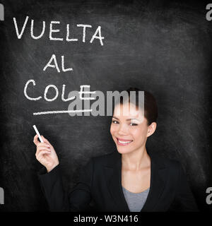 Vuelta al cole - professeur d'Espagnol femme. Retour à l'école écrit en espagnol sur tableau noir par femelle sur tableau. Le professeur femme l'enseignement de l'espagnol à l'université de langue, l'école secondaire ou une école primaire. Banque D'Images