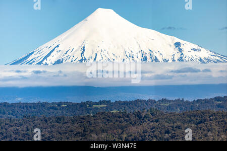 L'incroyable sommet enneigés volcan Osorno au-dessus des eaux et les nuages à partir de Puerto Plata, les arbres à l'intérieur de la forêt et les nuages d'un paysage Banque D'Images