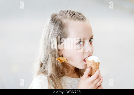 Liquez sur le yogourt glacé. Sweet Tooth fille manger une glace. Kid avec cornet de crème glacée dans la main. Blanc enfant glaces en cornet gaufré. Traite d'été concept. Enfance heureuse. Acheter de la crème glacée de l'alimentation de rue. Banque D'Images