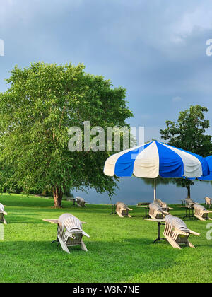 Parasols à l'heure d'or sur l'herbe avec des chaises empilées. Les chaises sont soigneusement empilées. Pas de personnes Banque D'Images