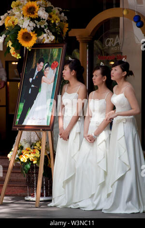 Demoiselles vêtues de blanc attendent la promise à l'extérieur du Grand Hôtel au centre-ville de Ho Chi Minh Ville au Vietnam du Sud Asie Banque D'Images