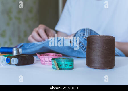 Women's Hands, un tailleur coud des vêtements à une table sur laquelle se trouvent des bobines de fil Banque D'Images