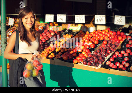 Femme d'acheter des fruits et des légumes au marché de fermiers. Candid portrait of young woman shopping for healthy lifestyle. Caucase Asie multiraciale modèle féminin. Banque D'Images