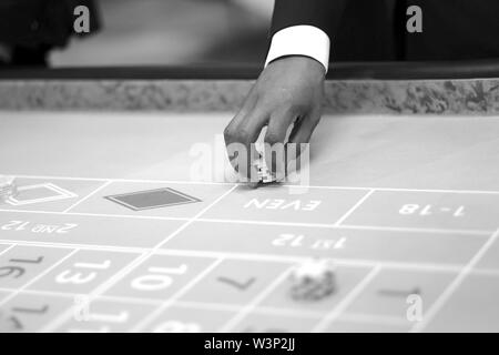 Main croupier avec jetons sur la table de jeu au casino Banque D'Images