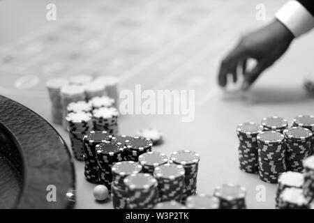 Main croupier avec jetons sur la table de jeu au casino Banque D'Images