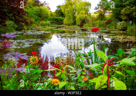 Beau jardin avec étang et de parterres de fleurs en grappes, variété d'arbres et arbustes en été à Giverny. Banque D'Images