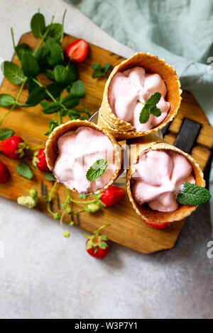 Fraise de boules de glace dans des cônes de lumière sur une table d'ardoise ou de pierre. Espace libre pour votre texte. Banque D'Images