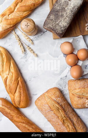 Variété de pain sur marbre blanc avec l'oeuf. Copie cercle espace pour texte, cornet autour, télévision, vue d'en haut. Concept de bannière de boulangerie Banque D'Images