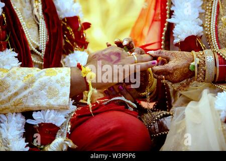 Mariée avec Bijoux de mariée et décoration au henné sur sa main se fixe à l'anneau du doigt de mariés cérémonie religieuse traditionnelle à un mariage hindou Banque D'Images