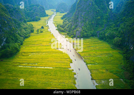 Image aérienne de Tam Coc au moment de la récolte, où les touristes peuvent croisière le long d'un ruisseau avec de belles rizières à côté. Banque D'Images