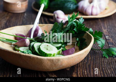 Bol de concombres biologiques fraîchement cueillies et l'ail, une salade fraîche avec des légumes et le persil sur table rustique à base de plantes, nourriture, Close up, s Banque D'Images