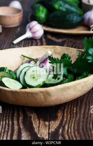 Bol de concombres biologiques fraîchement cueillies et l'ail, une salade fraîche avec des légumes et le persil sur table rustique à base de plantes, nourriture, Close up, s Banque D'Images